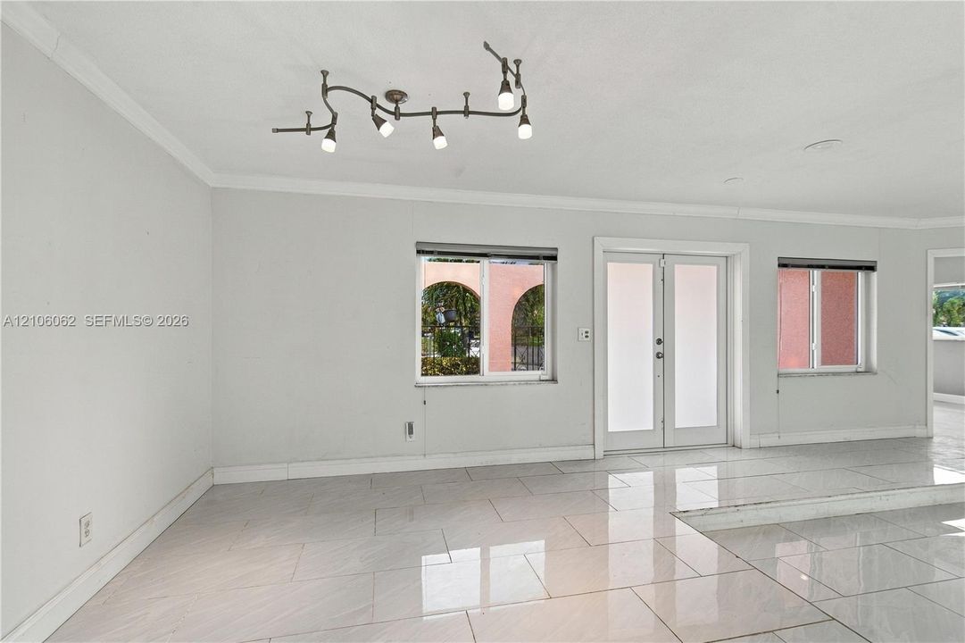 Polished tile flooring throughout, multi-light serpentine ceiling fixture, double glass-pane doors, and dual-pane windows with integrated hardware