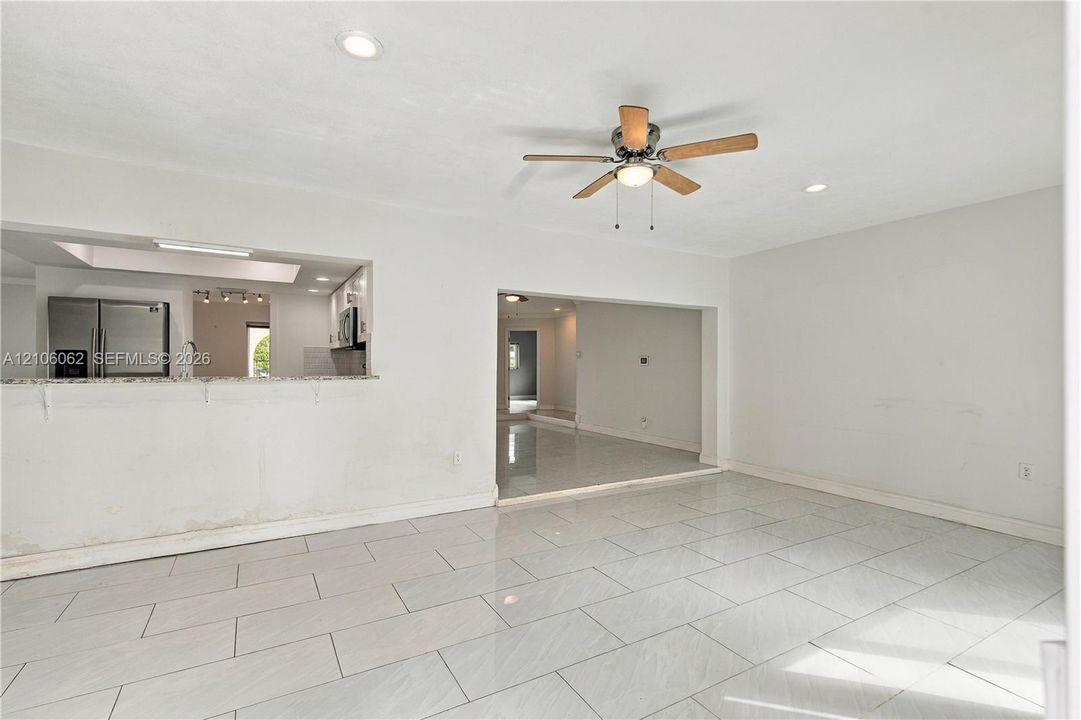 Polished tile flooring, recessed ceiling lighting, a multi-blade ceiling fan, and an open-concept pass-through counter