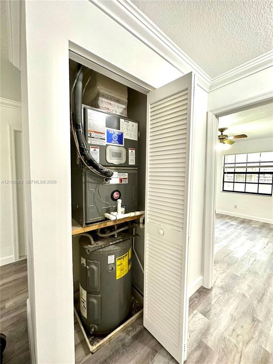 Utility closet featuring a white louvered door, a dedicated furnace unit, and a water heater