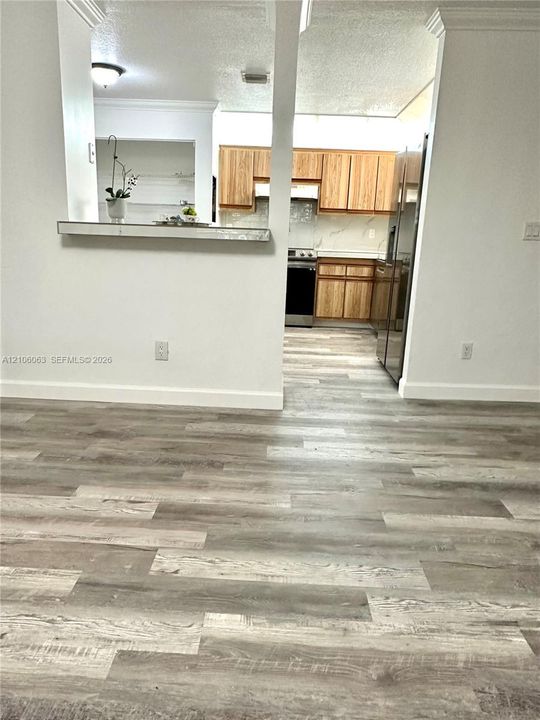 Kitchen featuring wood-finish cabinetry, stone-style countertops, stainless steel appliances, and wood-finish flooring