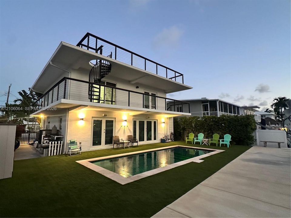 Multi-level exterior featuring a private in-ground pool, expansive rooftop deck with cable railings, integrated spiral staircase, and exterior wall-mounted lighting