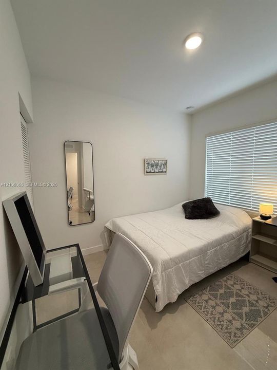 Room featuring neutral wall paint, large window with horizontal blinds, and closet with louvered doors