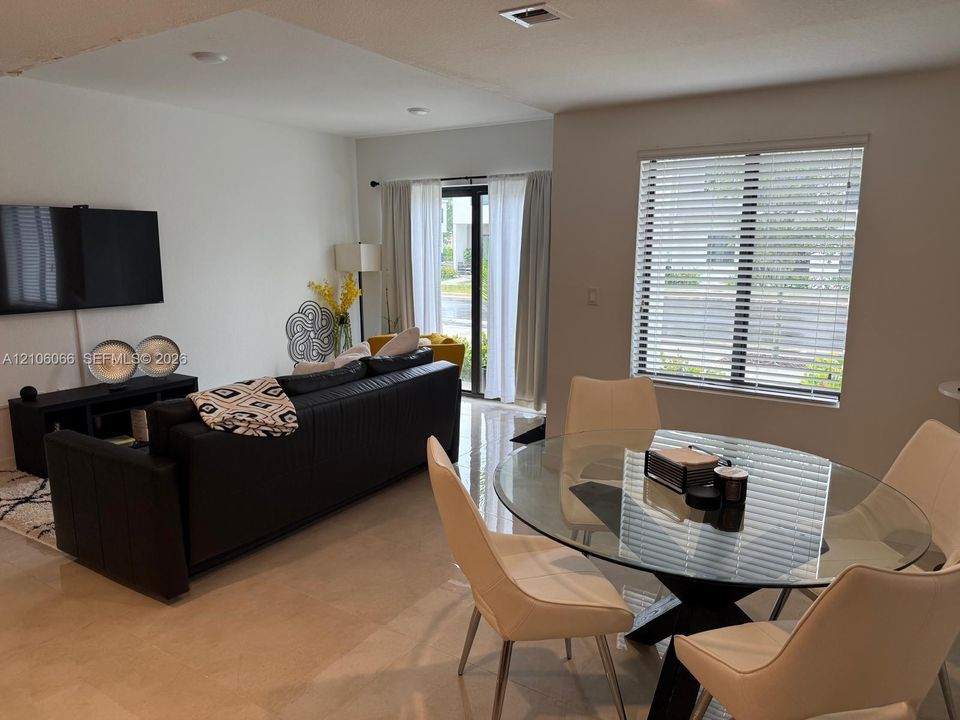 Open-concept floor plan featuring large-format tile flooring, recessed ceiling lighting, and a glass-paneled sliding door