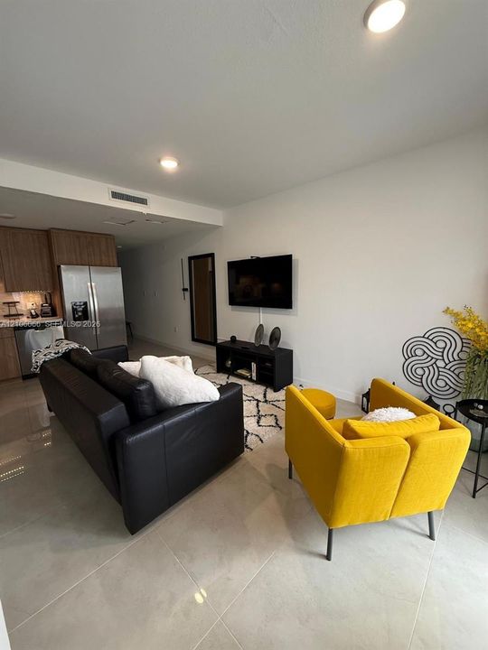 Large-format tile flooring, recessed ceiling lighting, and stainless steel kitchen appliances