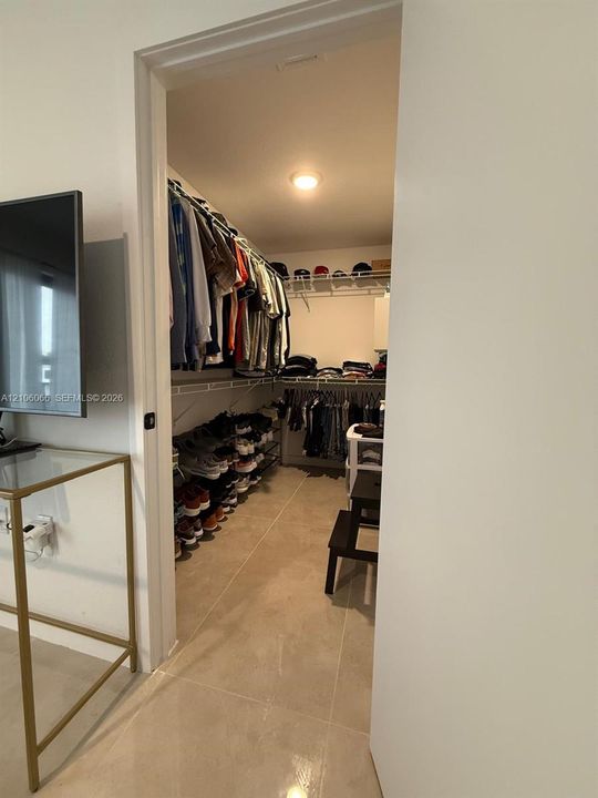 Walk-in closet featuring floor-to-ceiling shelving, tiered wire racking, and neutral tile flooring