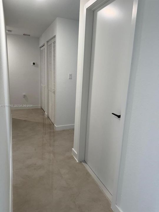 Large-format tile flooring, crisp white interior finishes, and dual louvered-panel closets featuring matte black door hardware