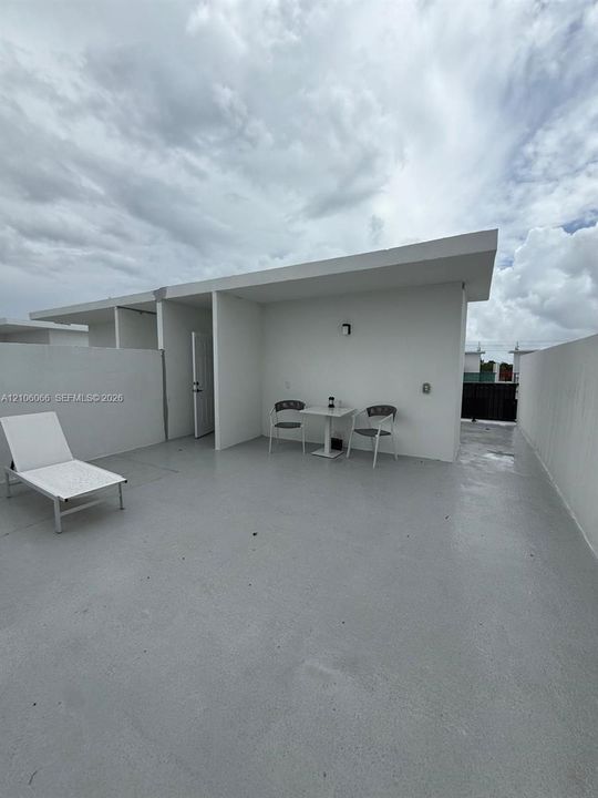 Rooftop terrace featuring a smooth-finish concrete deck, minimalist white structural walls, and integrated wall-mounted lighting