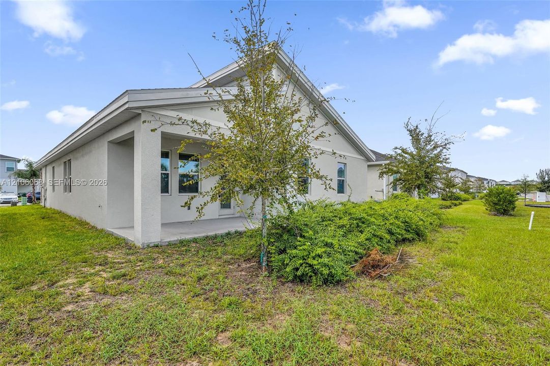 Stucco exterior featuring a covered patio, gabled roofline, and landscaped perimeter