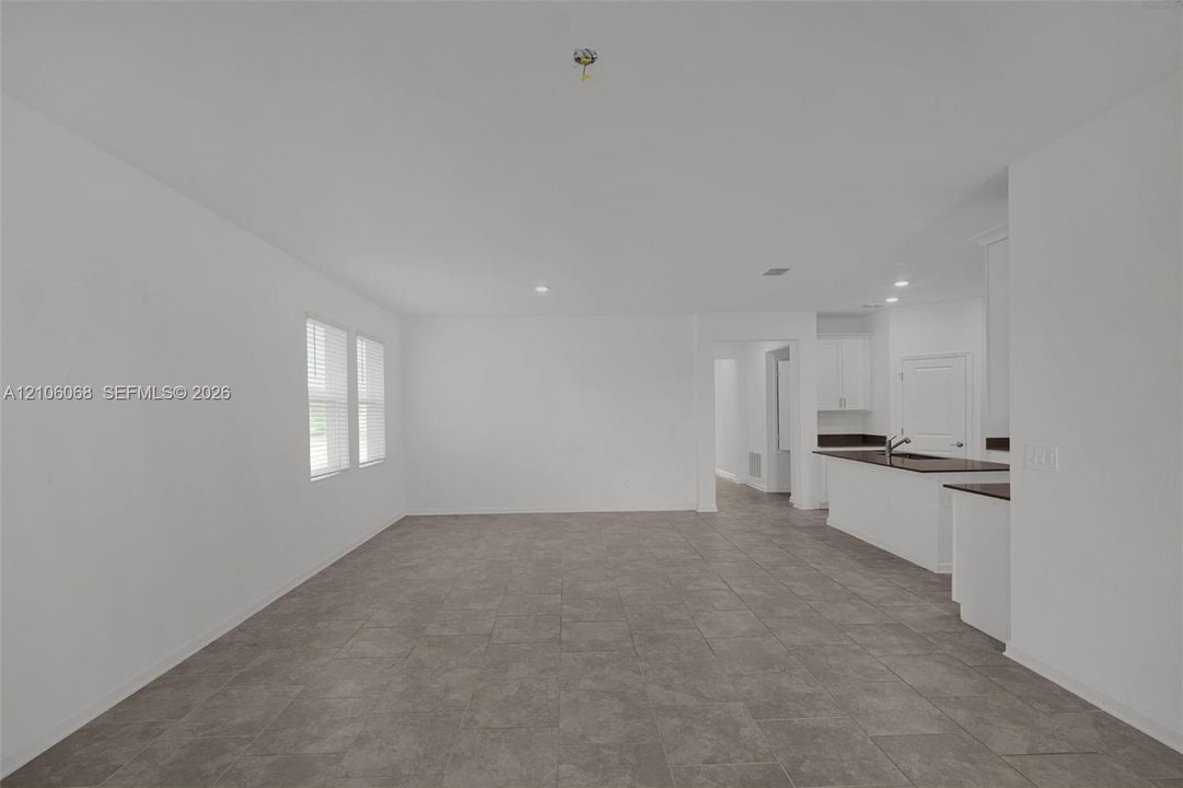 Neutral-toned ceramic tile flooring, recessed lighting, and kitchen island with dark countertops