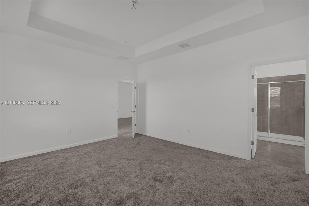Room featuring a tray ceiling, wall-to-wall carpeting, and neutral wall color
