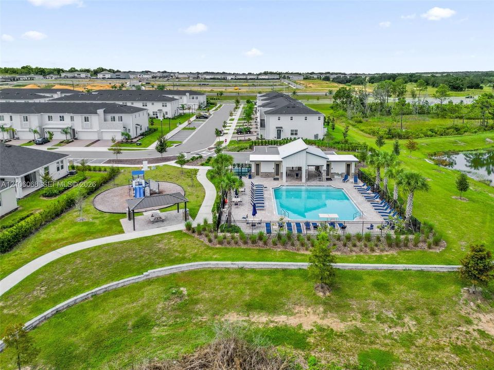 Community amenities featuring a swimming pool, covered outdoor pavilion, playground, concrete walking paths, and landscaped green space