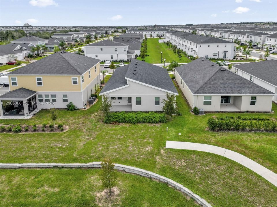 Aerial perspective of residential exteriors featuring gable rooflines, exterior stucco siding, covered concrete patios, and established landscaping
