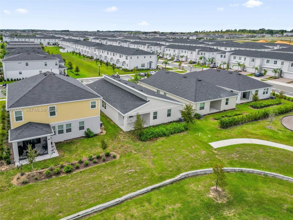 Aerial perspective of residential structures featuring multi-story siding exteriors, composite shingle roofing, integrated covered patios, and concrete walkways surrounded by landscaped grounds