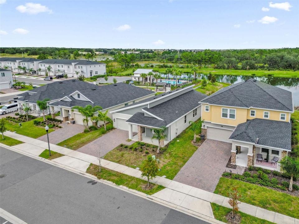 Residential exterior featuring multi-story structure with shingled roof, paver driveway, covered front entry, and stucco facade