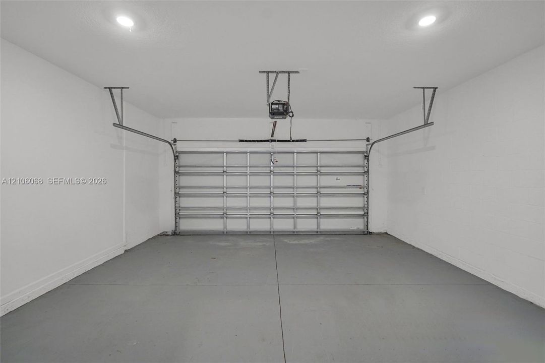 Finished garage featuring smooth white walls, recessed ceiling lighting, a concrete floor, and an automated overhead door system