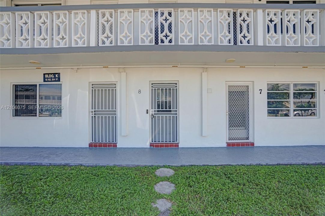 Exterior featuring decorative geometric balcony railing, horizontal sliding windows, metal security screen doors, and red brick entry thresholds