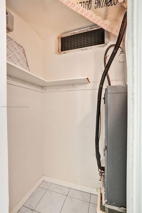 Utility room featuring tile flooring, built-in shelving, and exposed mechanical unit