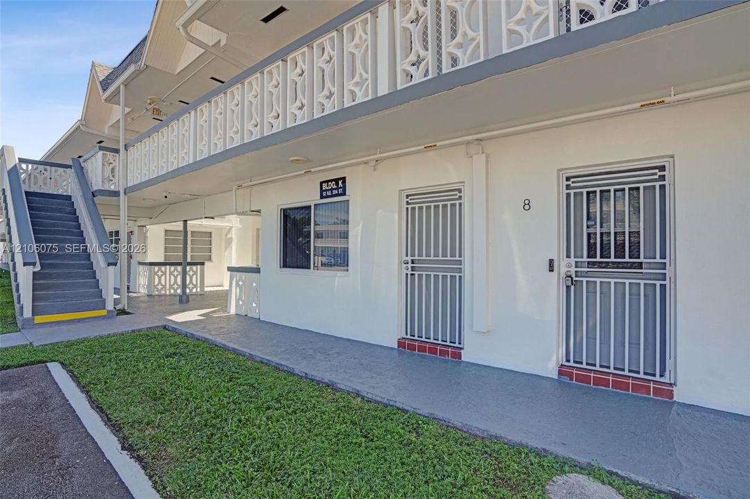 Exterior facade featuring decorative lattice railings, metal security screen doors, and an open-air staircase with concrete steps