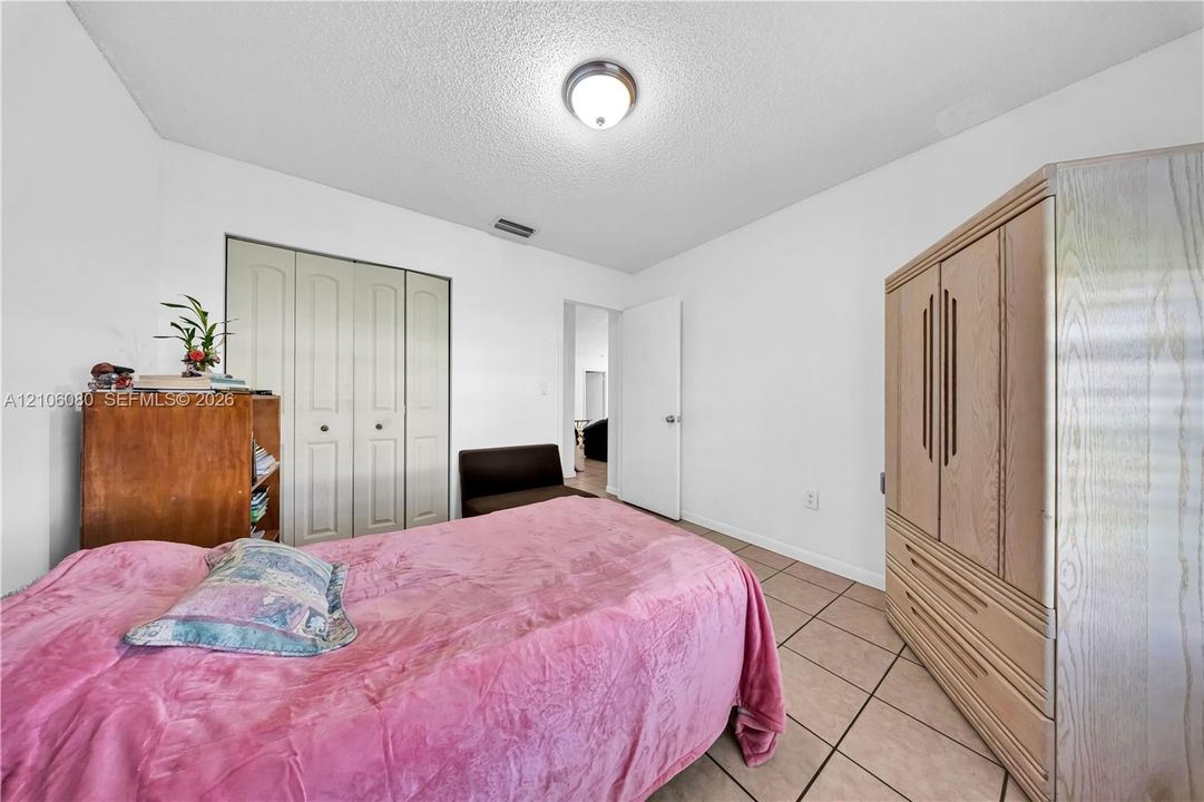 Room featuring ceramic tile flooring, neutral walls, flush-mount ceiling lighting, and a closet with bifold doors