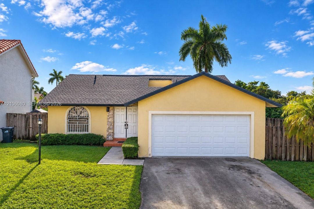 Single-story residence featuring a shingle roof, arched window with decorative grille, stone-veneer accent, and attached two-car garage