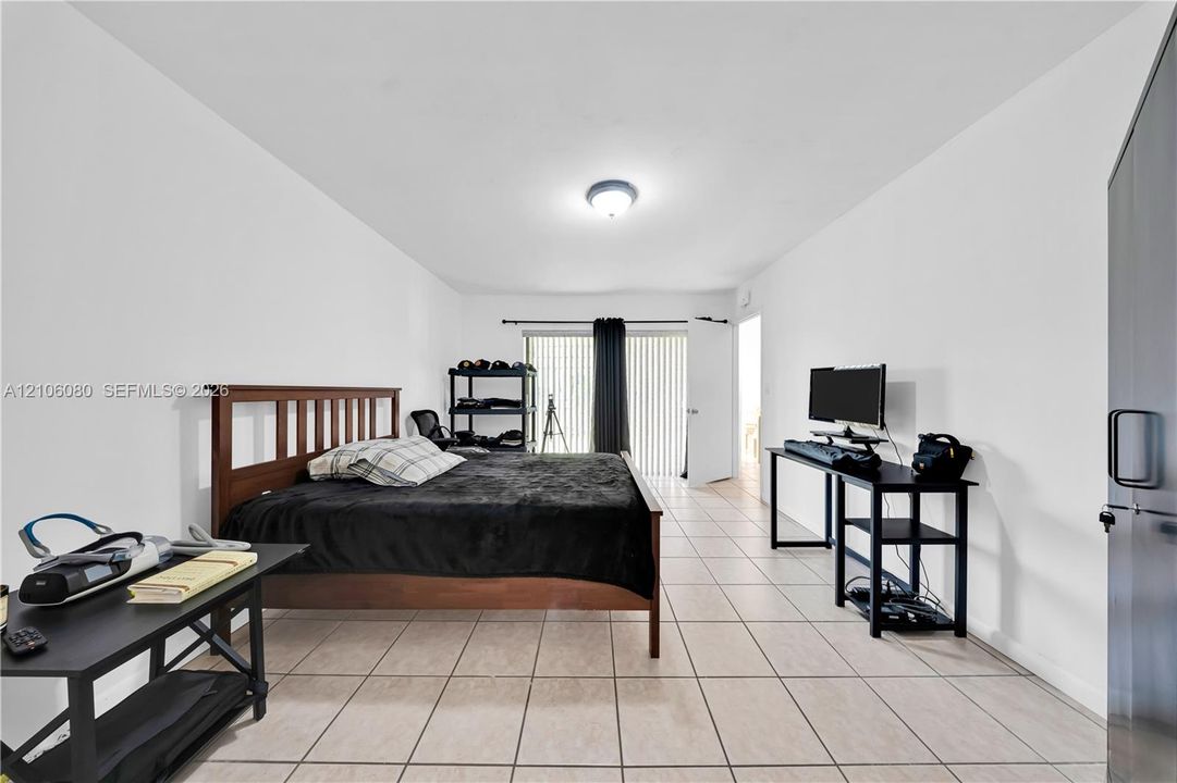 Neutral-toned ceramic tile flooring, flush-mount ceiling lighting, and sliding glass door with vertical blinds