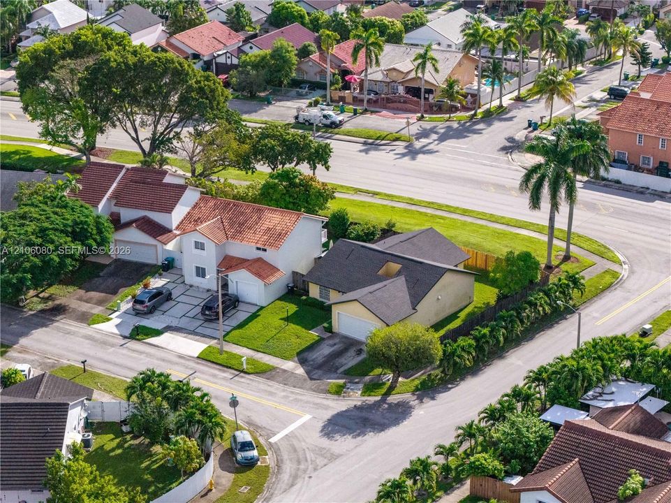 Corner lot property featuring a multi-car paved driveway, attached garage, tile and shingle rooflines, and manicured landscaping