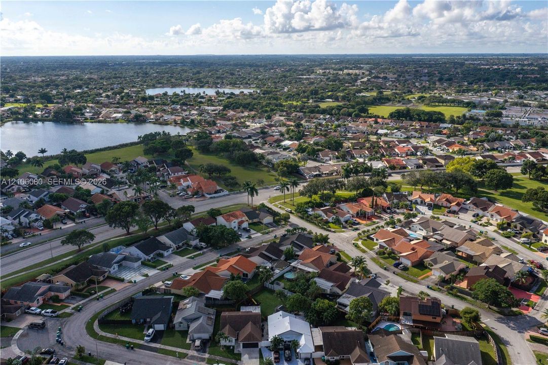 Aerial view of a residential community featuring winding paved streets, multiple freshwater ponds, and mature tree-lined landscapes