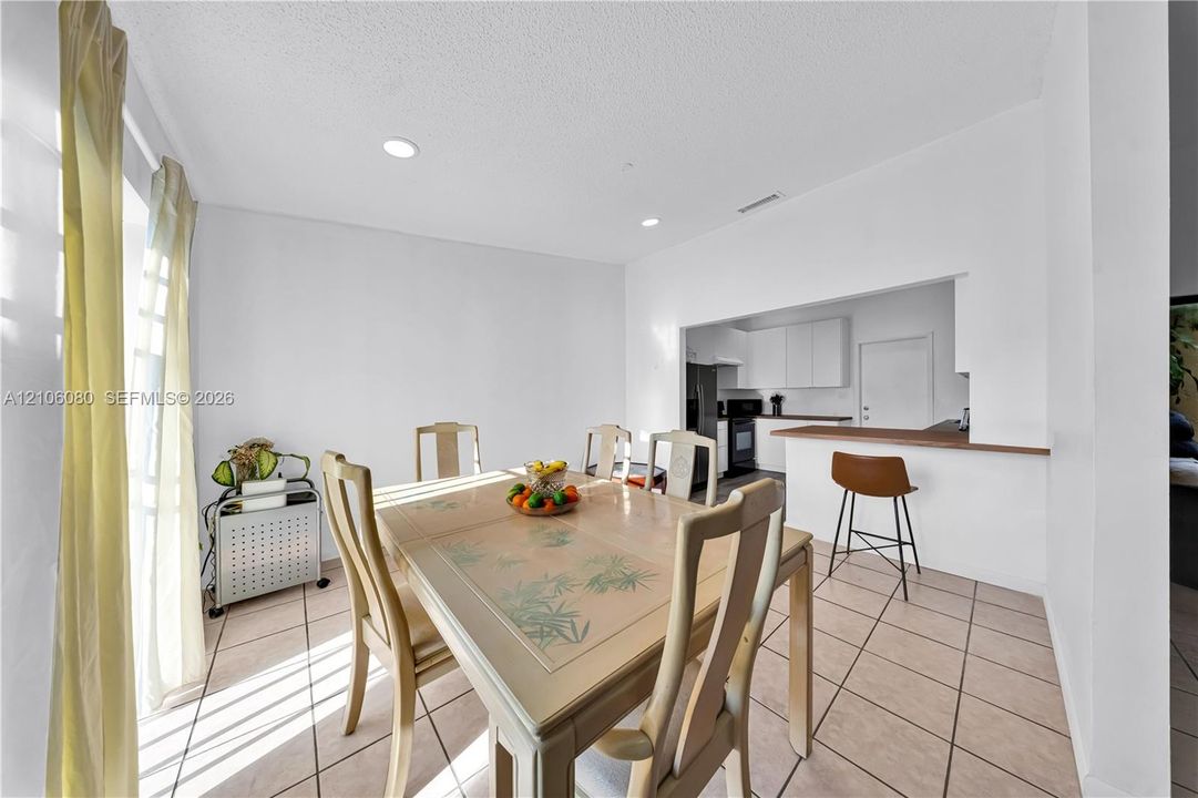 Ceramic tile flooring, recessed lighting, and a breakfast bar with a wood-finish countertop