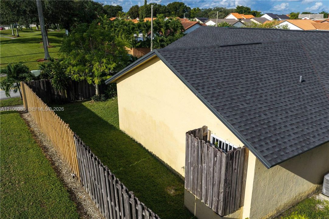 Exterior side yard featuring a wood privacy fence and asphalt shingle roofing