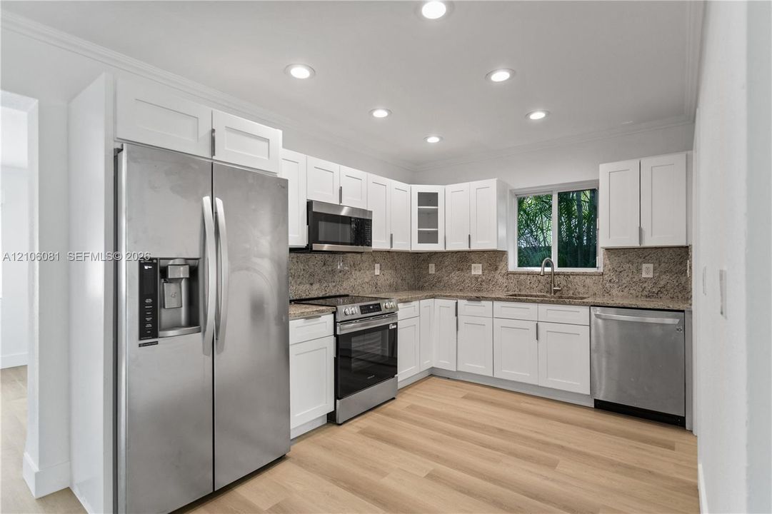 Kitchen featuring white cabinetry, stone countertops, stainless steel appliances, recessed lighting, and wood-finish flooring