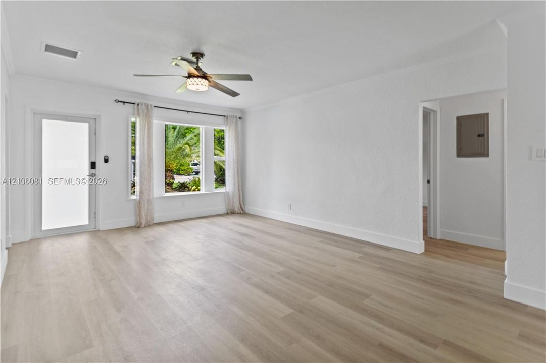 Interior space featuring wood-finish flooring, a multi-pane window, a glass-panel exterior door, and an overhead ceiling fan