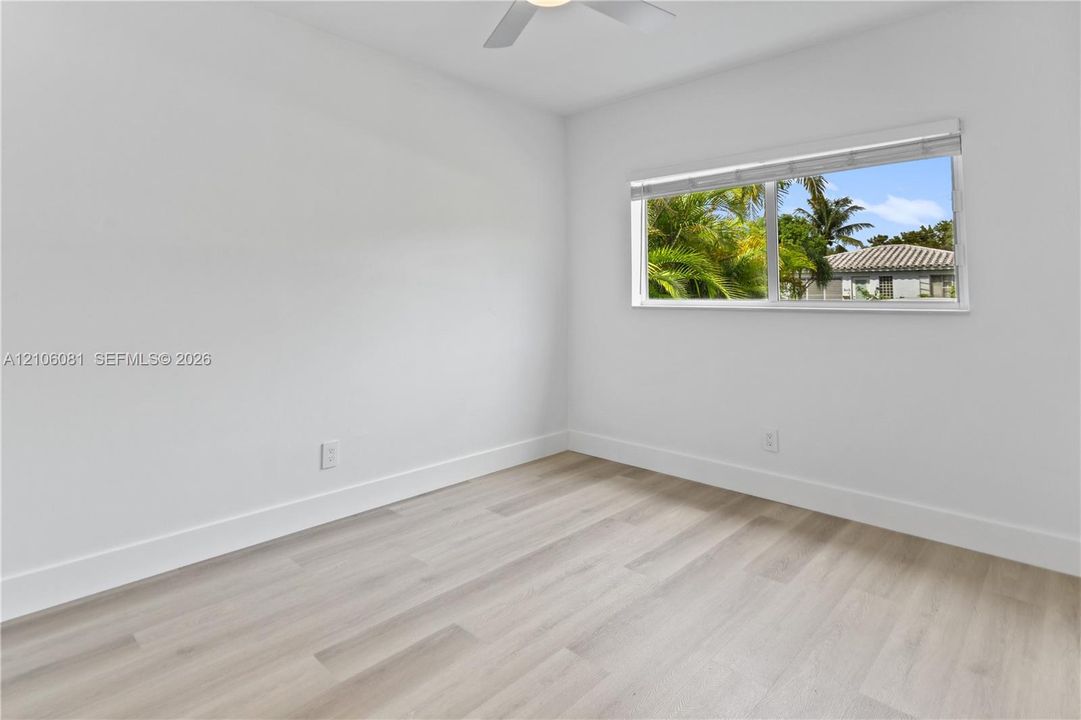 Interior room featuring light wood-finish flooring, neutral walls, a ceiling fan, and a horizontal window with adjustable blinds