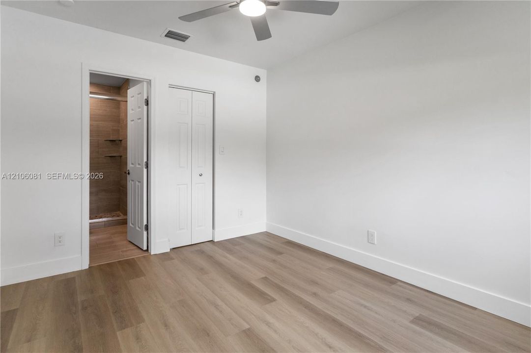 Room featuring wood-finish flooring, a ceiling fan with integrated lighting, and a bi-fold closet door