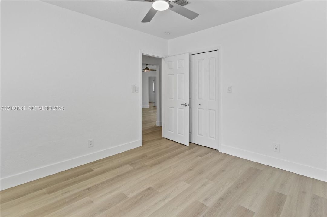 Room featuring light-tone wood-finish flooring, a ceiling fan with integrated lighting, and a six-panel closet door