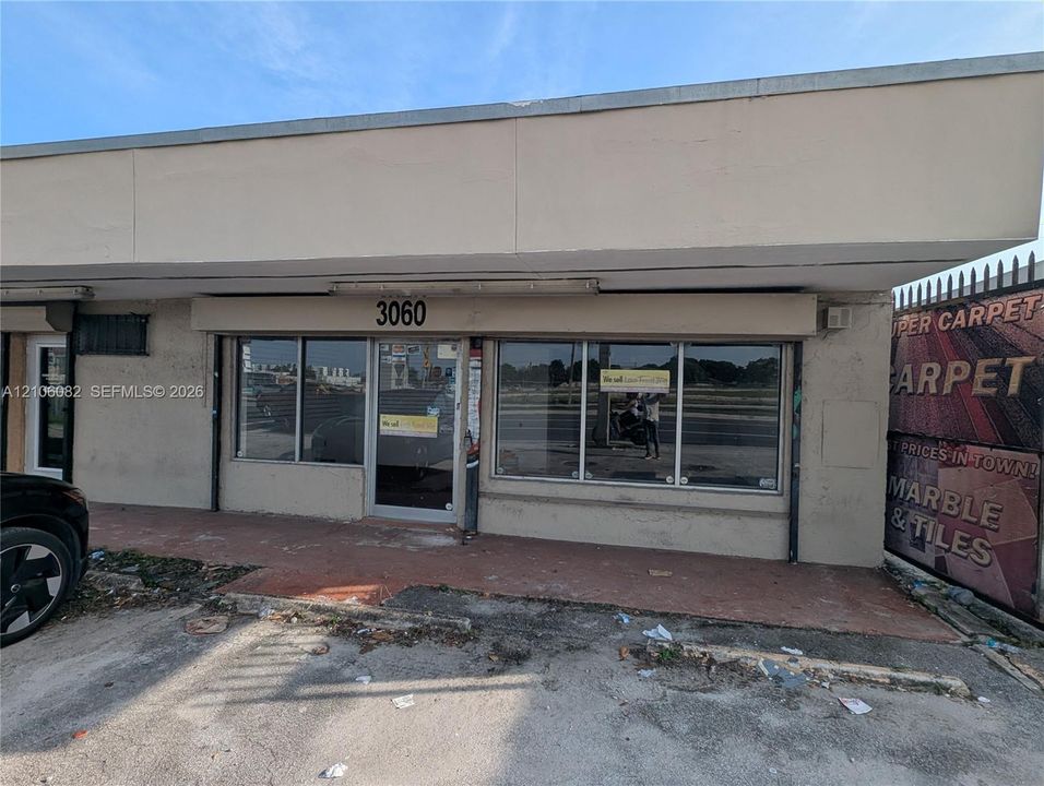 Commercial storefront featuring a flat roofline, floor-to-ceiling plate glass windows, and a glass-paneled entrance door