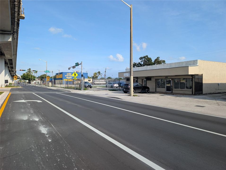 Single-story commercial building featuring a flat roofline, stucco exterior, and multi-pane storefront glass windows, situated on a paved lot with prominent street frontage