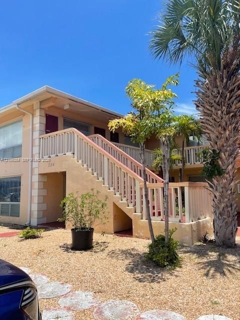 Stucco exterior with multi-level wood railing staircase providing direct access to upper and lower decks