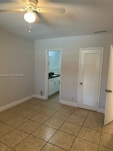 Ceramic tile flooring, ceiling fan with integrated lighting, and louvered closet door