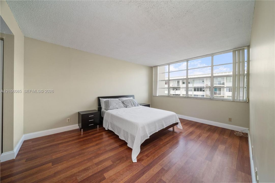 Spacious room featuring wood-finish flooring and expansive multi-pane windows with vertical blinds