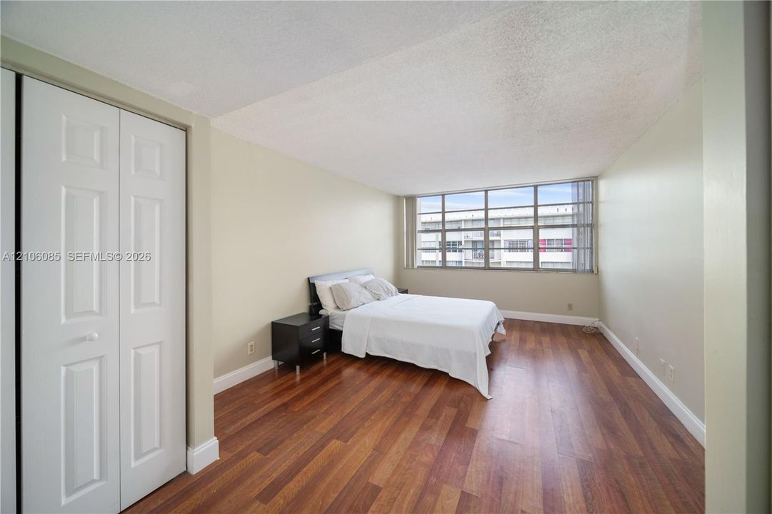 Room featuring wood-finish flooring, floor-to-ceiling multi-pane windows, and a built-in double-door closet