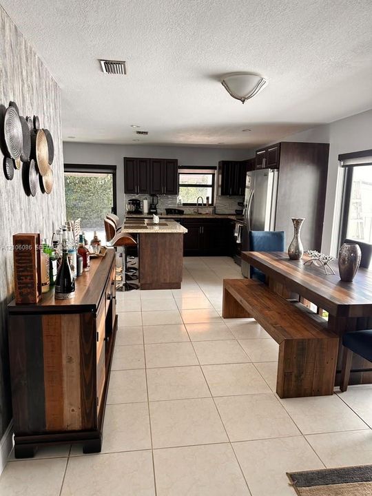 Kitchen featuring dark cabinetry, stone-finish countertops, a central island, and ceramic tile flooring
