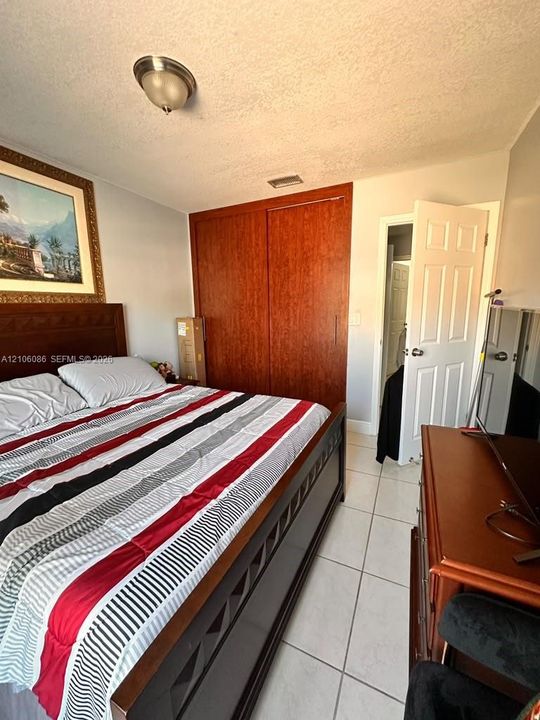 Room featuring tile flooring, wood-finish sliding closet doors, and a flush-mount ceiling light fixture