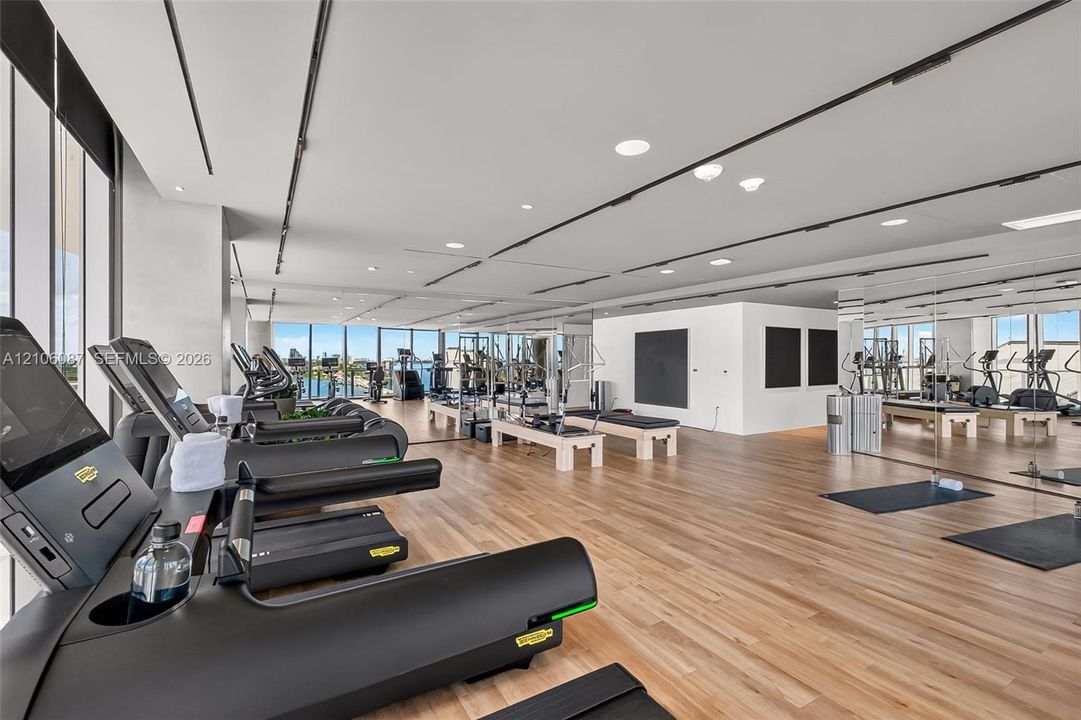 Fitness center featuring floor-to-ceiling windows, wood-finish flooring, full-wall mirrors, and recessed ceiling lighting