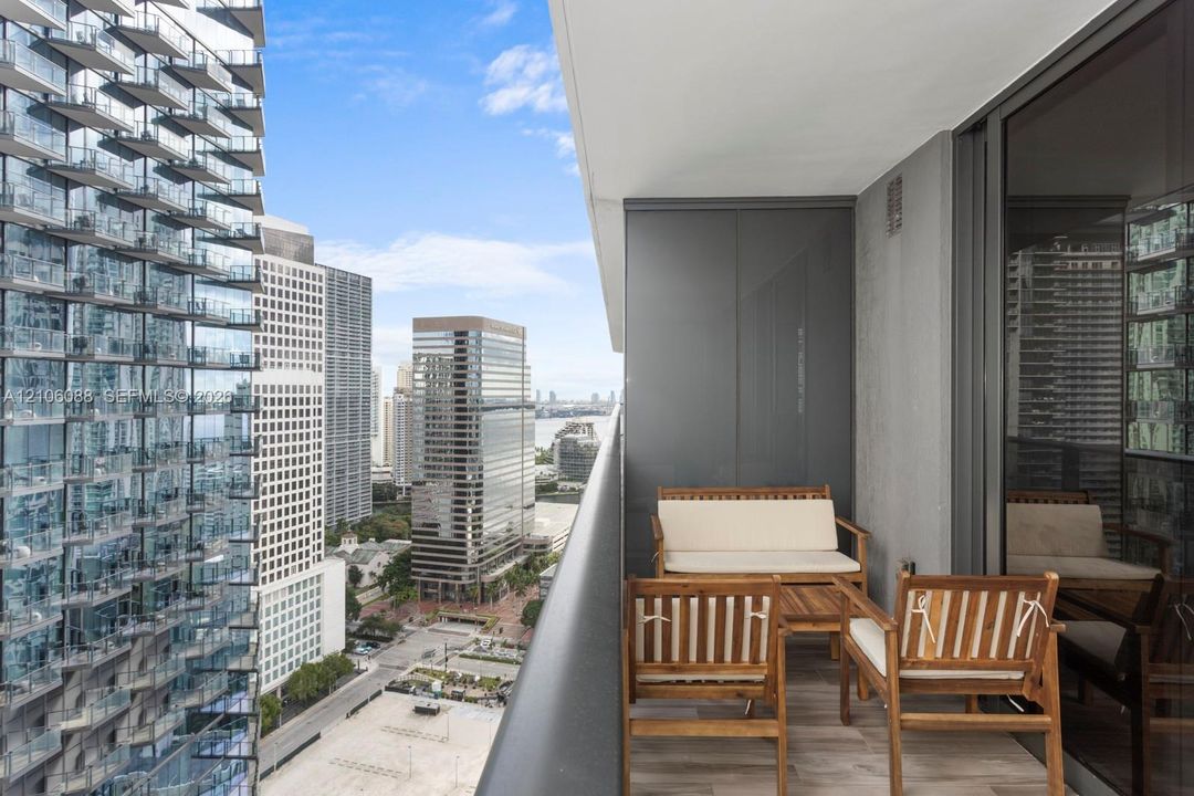 Private balcony featuring wood-finish flooring, metal railing, and high-rise urban surroundings