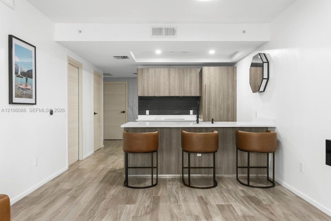 Kitchen featuring wood-finish cabinetry, a white countertop island, matte black faucet, and a hexagonal tile backsplash