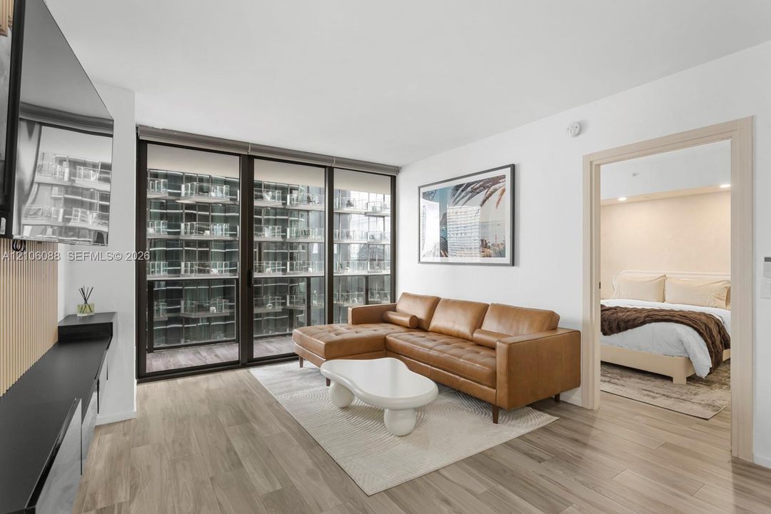 Floor-to-ceiling sliding glass doors, wood-finish flooring, and built-in matte black shelving