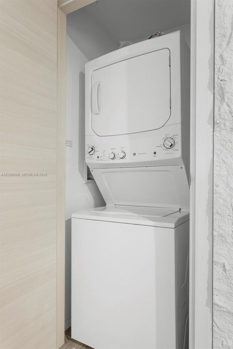 Stacked white laundry center featuring a top-loading washer and front-loading dryer with analog control dials