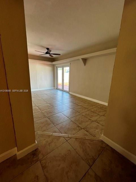 Large-format tile flooring, double glass-panel doors, and ceiling-mounted fan