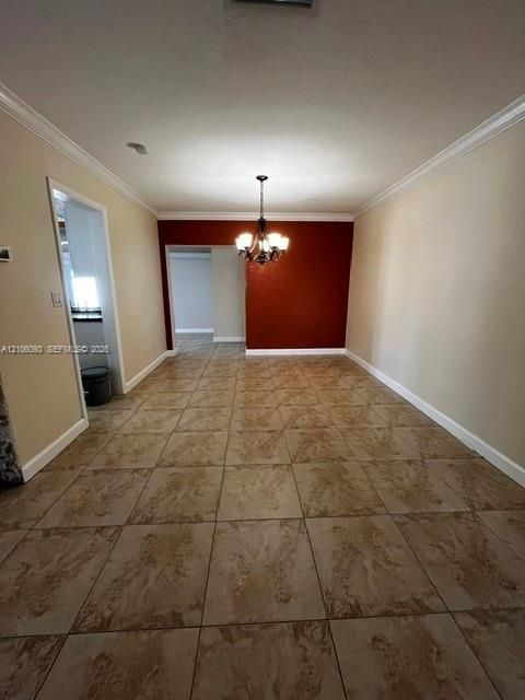 Large-format tile flooring, crown molding, and a multi-arm chandelier featuring clear glass shades