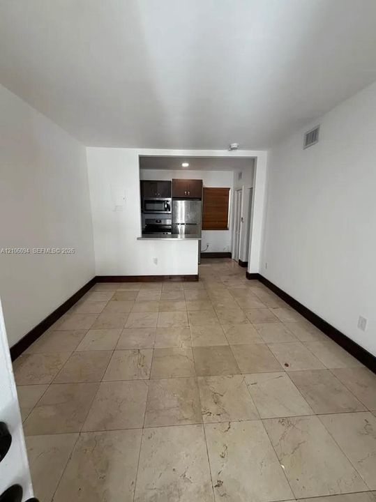 Interior area featuring large-format stone tile flooring, dark-toned cabinetry, stainless steel kitchen appliances, and a breakfast bar